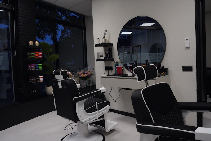 Interieur van House of Barbers Enschede met zwarte barberstoelen en grote ronde spiegel